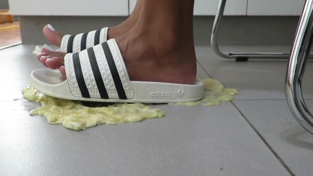 Enola crushing a banana with ADIDAS ADILLETE and foot feeding his slave.